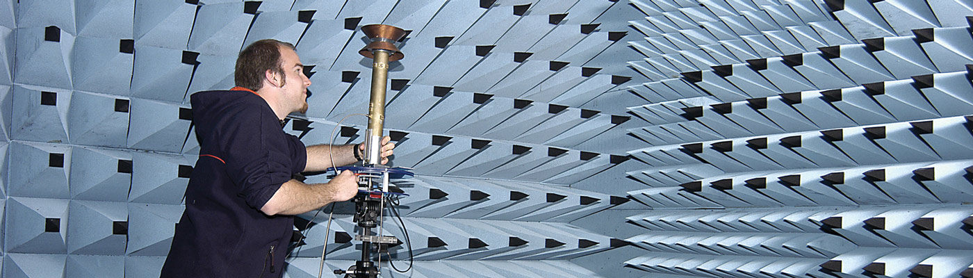 Man setting up equipment in light blue and black anechoic chamber
